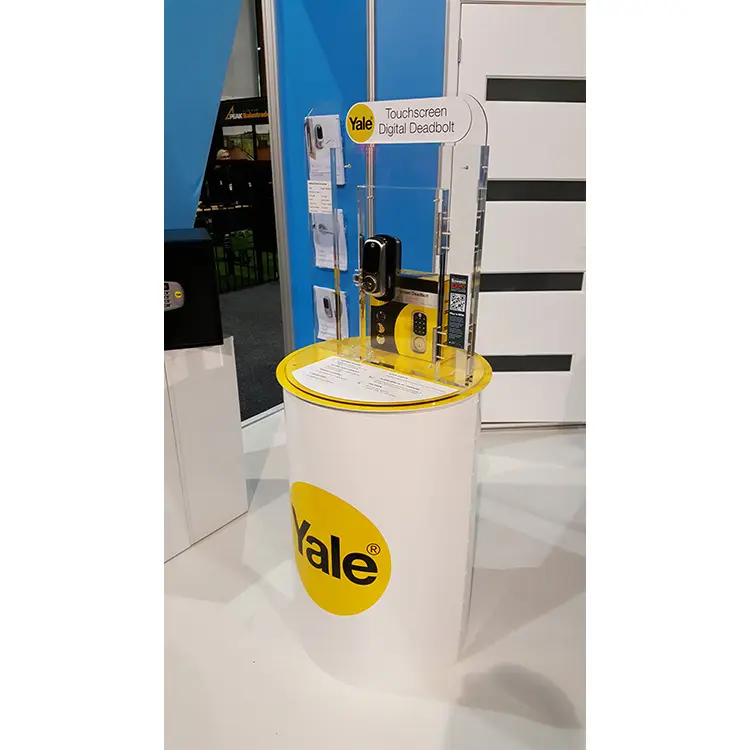 Yale digital deadbolt and packaging in a clear acrylic upright on a yellow-topped plinth