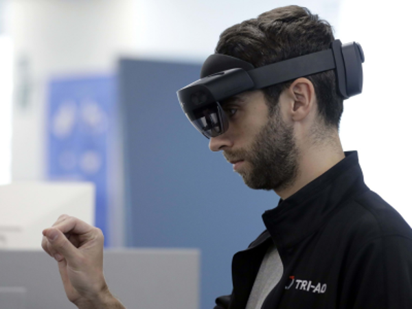 Man wearing a mixed reality headset and reaching out with one hand