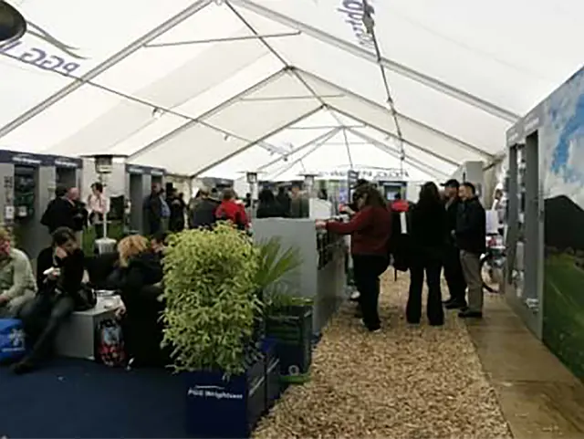 Long PGG Wrightson marquee lined with display stands along a bark-covered walkway