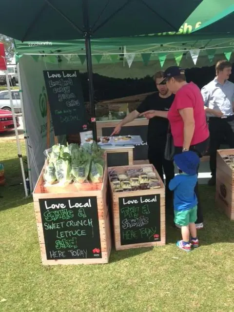 Woolworths Love Local crates of Sweet Crunch lettuce with chalkboard fronts beside a salad table