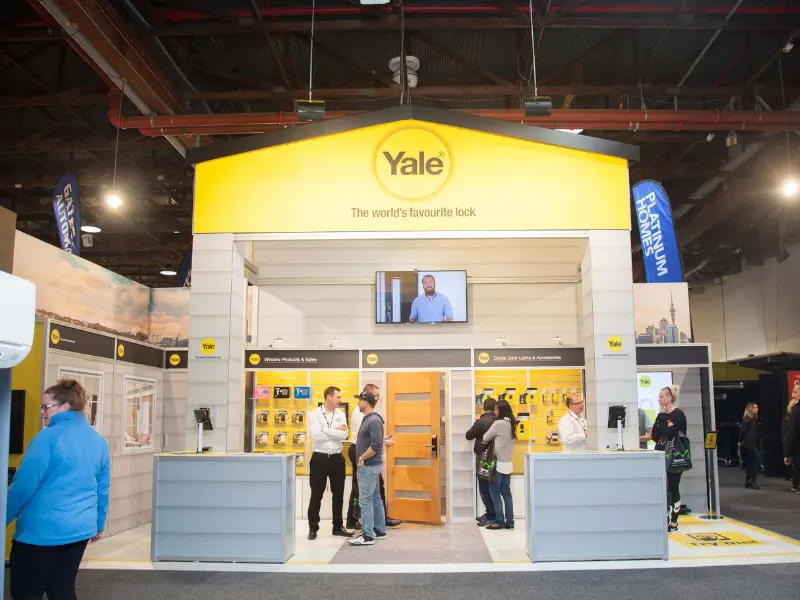 Yale expo booth with a yellow peaked roof, a timber door and two front counters