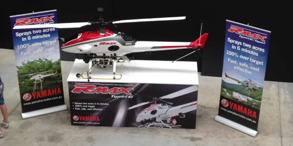 Yamaha RMAX helicopter on a display stand between two branded pull-up banners