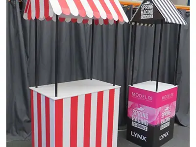 Two awning-roofed stall counters, one in red and white stripes and one with Lynx graphics