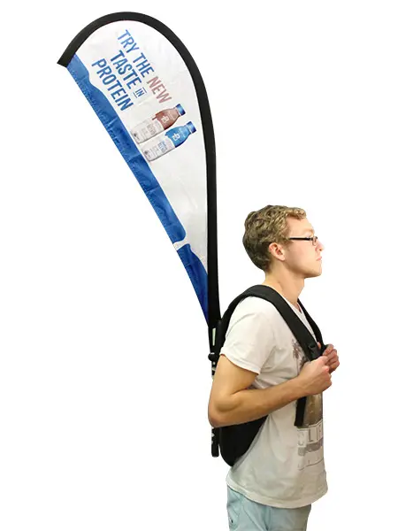 Promoter wearing a curved backpack flag printed with Try the new taste in protein
