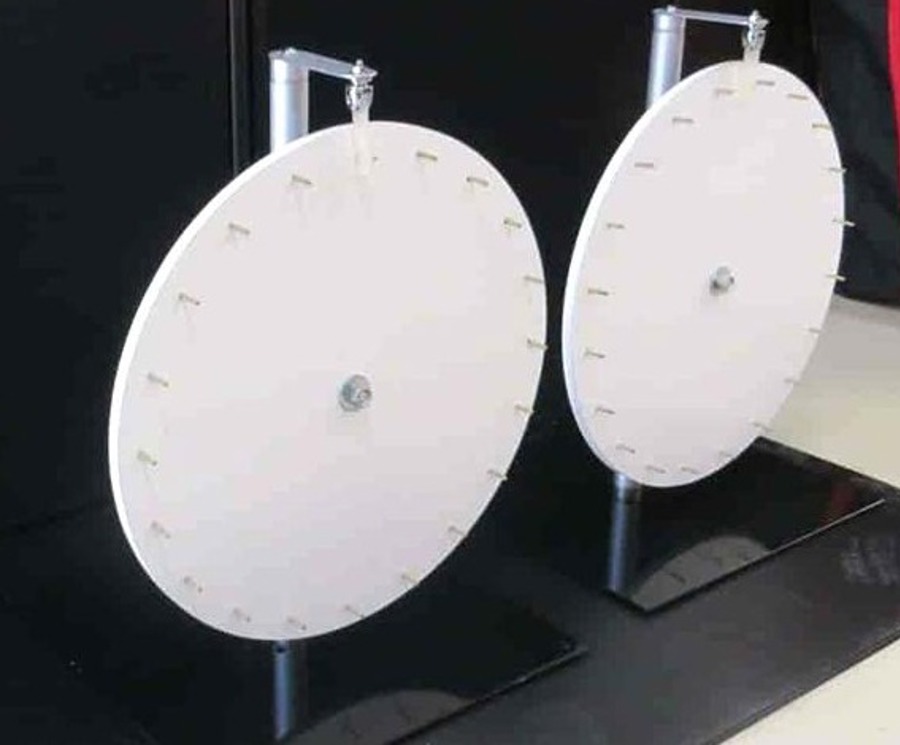 Two plain white spinning wheels with pegs around the rim, mounted on black stands
