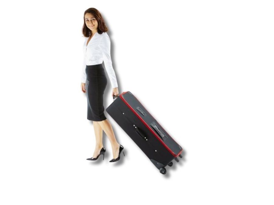 Woman pulling a black wheeled carry case with a red trim along behind her