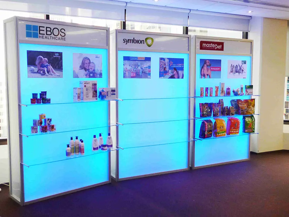 Three blue-backlit display cabinets with glass shelves for EBOS Healthcare, Symbion and Masterpet
