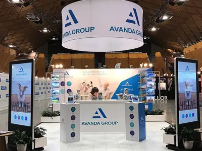Circular Avanda Group banner hung above a white stand with digital totems at each corner