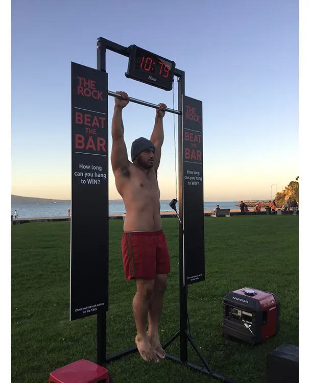 The Rock Beat the Bar hanging frame with a digital timer above and black signs