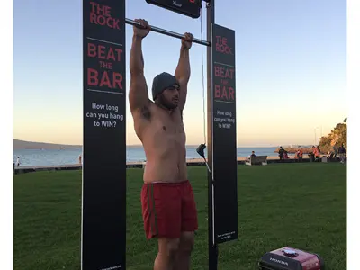 The Rock Beat the Bar hanging frame with a digital timer above and black signs