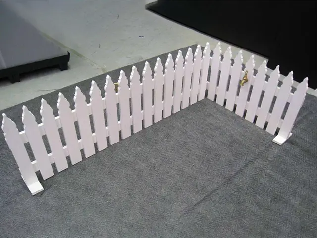 White freestanding picket fence set out as a corner, standing on flat feet