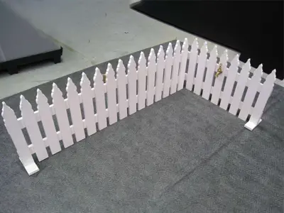 White freestanding picket fence set out as a corner, standing on flat feet
