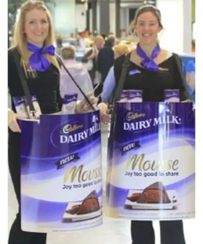 Promoters carrying Cadbury Dairy Milk Mousse tubs with packs standing in the open tops