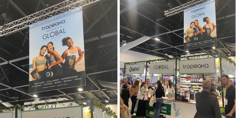 Large printed Tropeaka Global fabric banner hanging over the busy stand at Naturally Good Expo