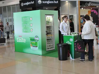 Green Symbio yoghurt pop up shop with a glass-door fridge and a counter in front