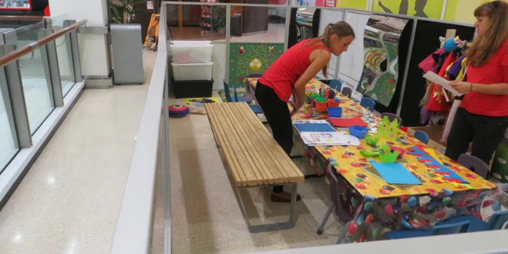 Staff setting up craft activities on the bench inside the Eventful Kids booth