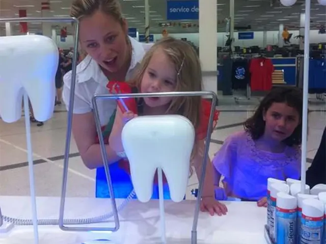 Oversized tooth models on metal frames at child height beside Macleans tubes in Kmart