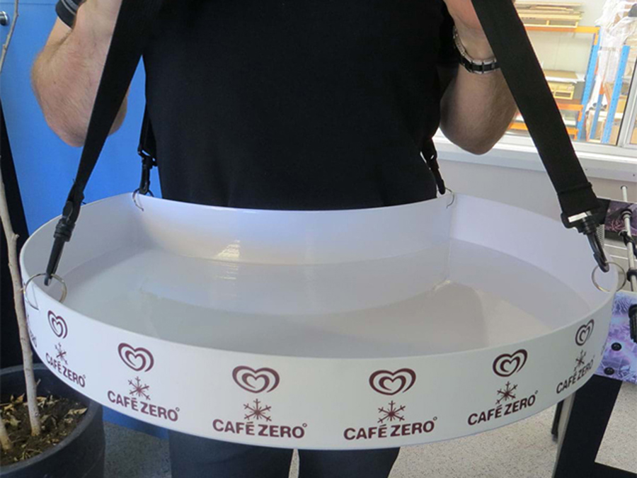 White vendor tray with a Café Zero branded graphic strip, worn at waist height on black adjustable shoulder straps