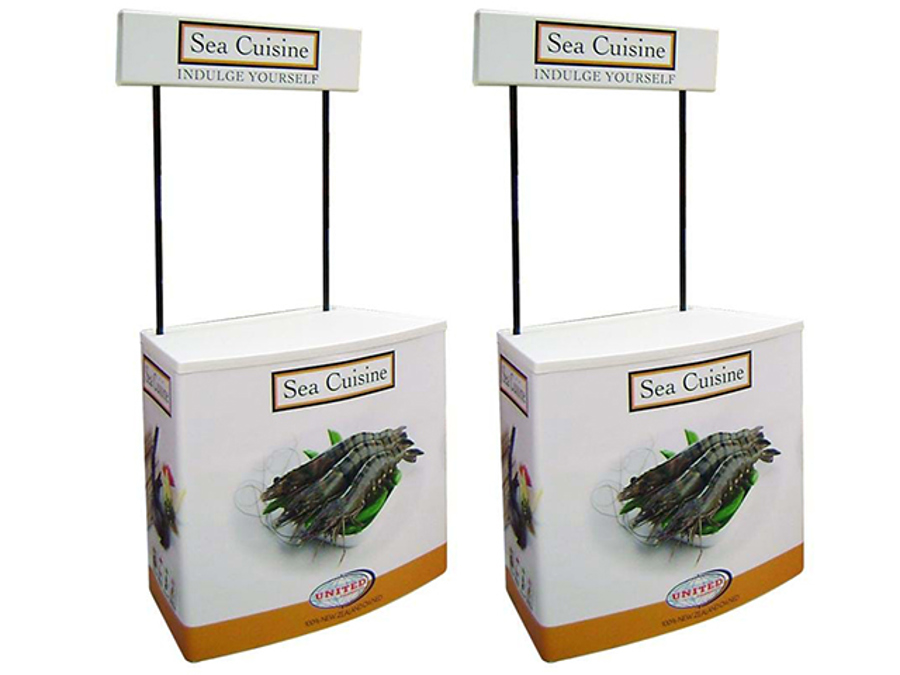 Two curved-front demonstration tables with Sea Cuisine prawn graphics on the base wraps and branded header boards on poles