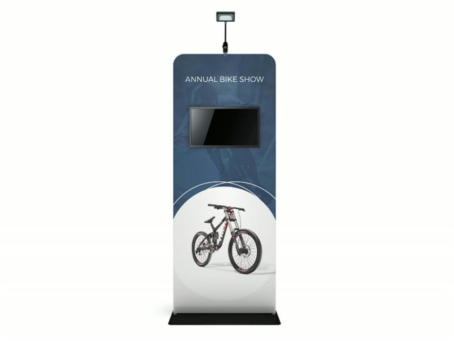 Product mock-up of a slim fabric banner stand on a black base plate, with a widescreen monitor set into the upper graphic, a mountain bike printed below and a small light on top