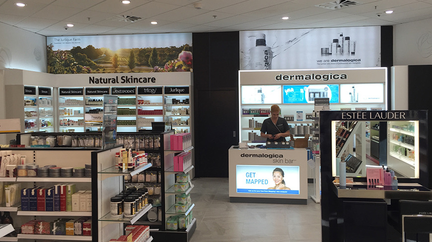 Dermalogica skin bar with an illuminated header and lit back shelves beside a skincare wall